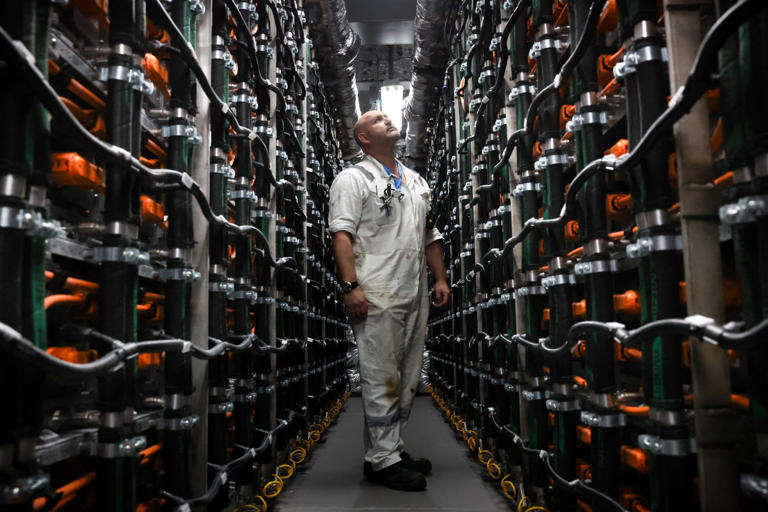 An engineer member of staff looks at the XALT Energy batteries of a capacity of up to 8.8 MWh placed in the battery room of the Hybrid Ferry ship P&O Liberte, docked in the port of Dover, southern England, on March 14, 2024. P&O Liberte and its sister ship Pioneer will be able to accommodate up to 15,000 passengers and 800 lane metres for cars. The new ferries will incorporate electric battery technology, reducing emissions and minimising environmental impact. To recharge the batteries efficiently, Calais and Dover terminals will have to be equipped with giant 40-megawatt charging stations. Calais, will benefit from being close to a nuclear power station, whilst for Dover, work will required to create high voltage lines to enable full use to be made of electric ferries. (Photo by Daniel LEAL / AFP) (Photo by DANIEL LEAL/AFP via Getty Images)
