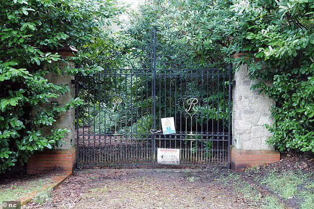 A gate on the estate with warning signs pinned to it. Some of the mansions on the estate have been left to rot 