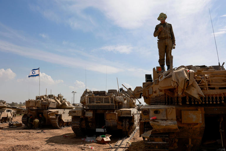 An Israeli soldier checks a mobile atop a tank in an army camp near Israel's border with the Gaza Strip on April 8, 2024, amid the ongoing conflict between Israel and the militant group Hamas.