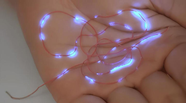 A researcher shows the luminous mechanism of new smart fiber at Donghua University in Shanghai, east China, in March 2024. (Donghua University/Handout via Xinhua)