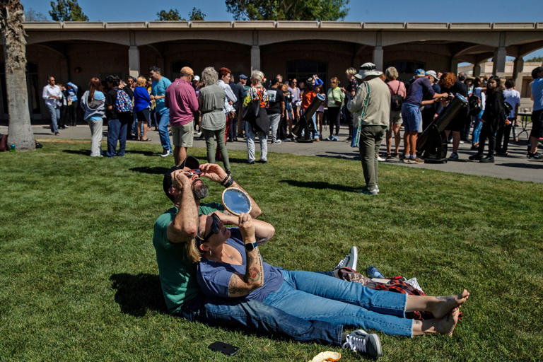 Nick Betten and Renae Walker of Riverside view the partial solar eclipse during an event hosted by the School of Mathematics and Science at College of the Desert in Palm Desert, Calif., on Monday, April 8, 2024.