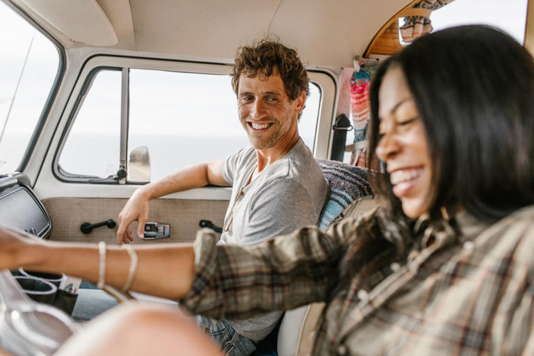 15 fun road trip games. Pictured: a woman smiling and driving and a man next to her smiling at her.