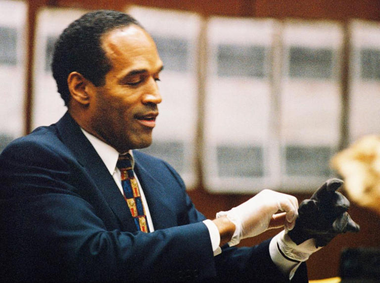 O.J. Simpson tries on a leather glove allegedly used in the murders of Nicole Brown Simpson and Ronald Goldman during testimony in Simpson's murder trial June 15, 1995 in Los Angeles.