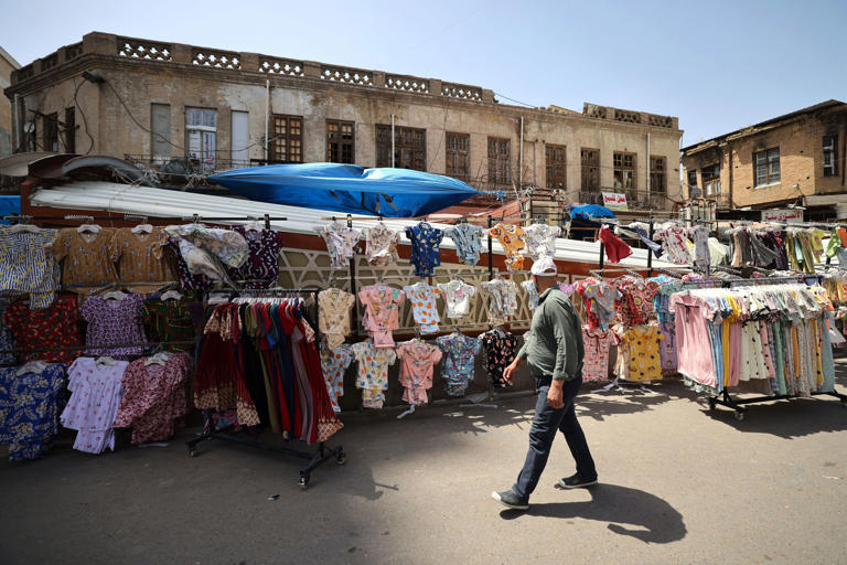 A man walks past clothes for sale at the Shorja market in downtown Baghdad ahead of Eid al-Fitr celebrations, marking the end of the Muslim holy fasting month of Ramadan, on April 9, 2024.