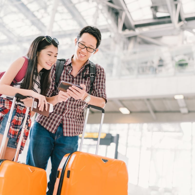 Traveling Couple Pictured In An Airport With Yellow Luggage