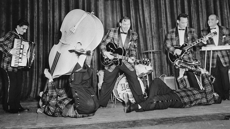 Bill Haley and His Comets rehearse at the Dominion Theatre in London, where they will open their British tour. The Comets include accordion player Johnnie Grande, bassist Al Rex, and saxophonist Ruddy Pompilli. Getty Images