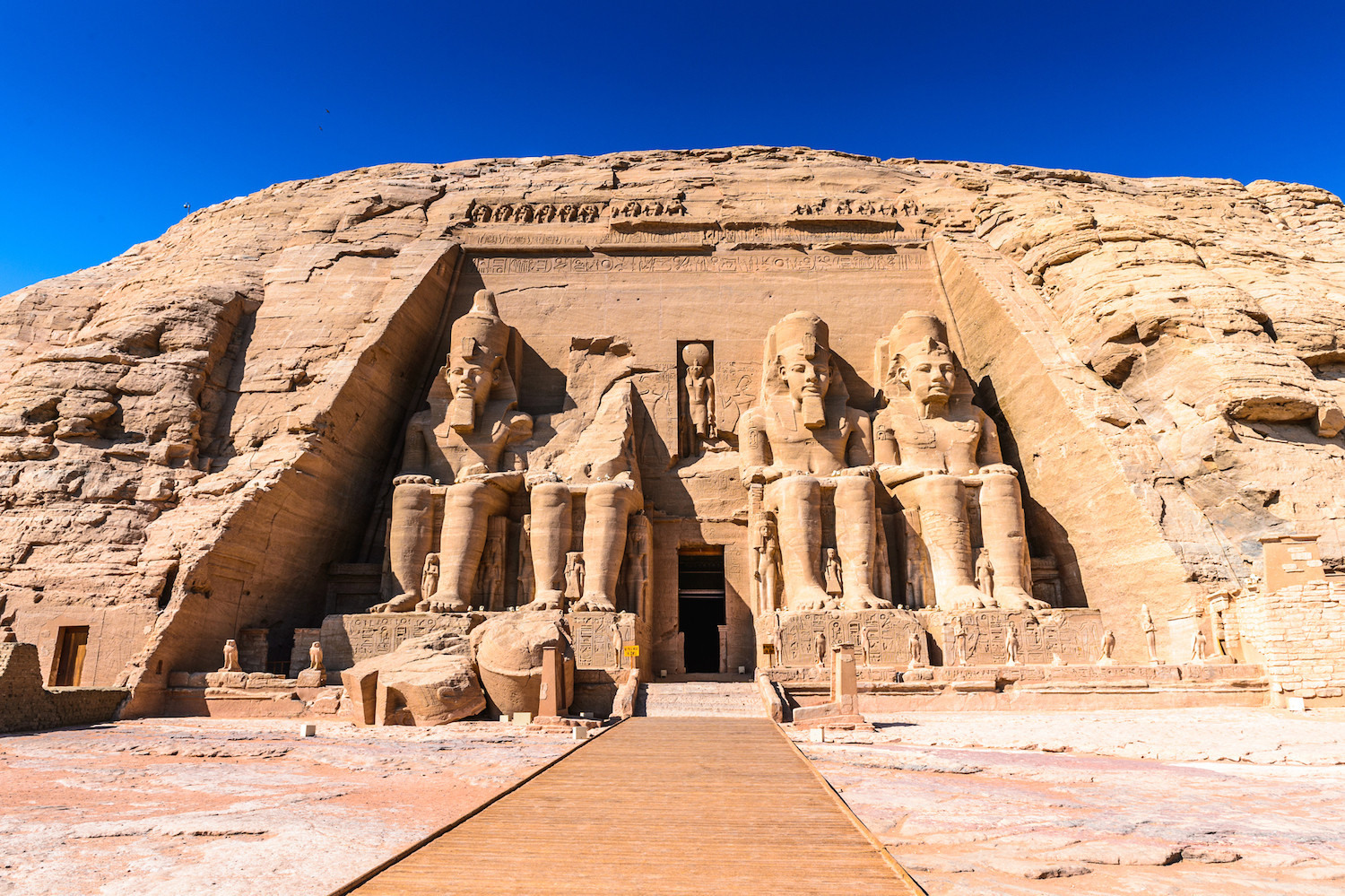 <p><span><span><span><span><span><span>During his reign in the 13th century BCE, Pharoah Ramses II commissioned Amu Simbel to create this monument. Cut from the rocky hillside, it features four gigantic statues of Ramesses II that flank the entrance. Abu Simbel was strategically placed so sunlight would enter the inner chamber twice yearly on each equinox. An earthquake caused the damage shown in the photo.</span></span></span></span></span></span></p>  <p><span><span><span><span><span><span>When the Aswan Dam was built in the 1960s and 70s, which created Lake Nasser, water would have covered the ruins in their original location. Therefore, archeologists moved the Abu Simbel temples to a higher spot known as the UNESCO Nubian Monuments. Despite the move, they did not reconstruct the damaged statue, preferring to leave the broken pieces just as they had fallen.</span></span></span></span></span></span></p>