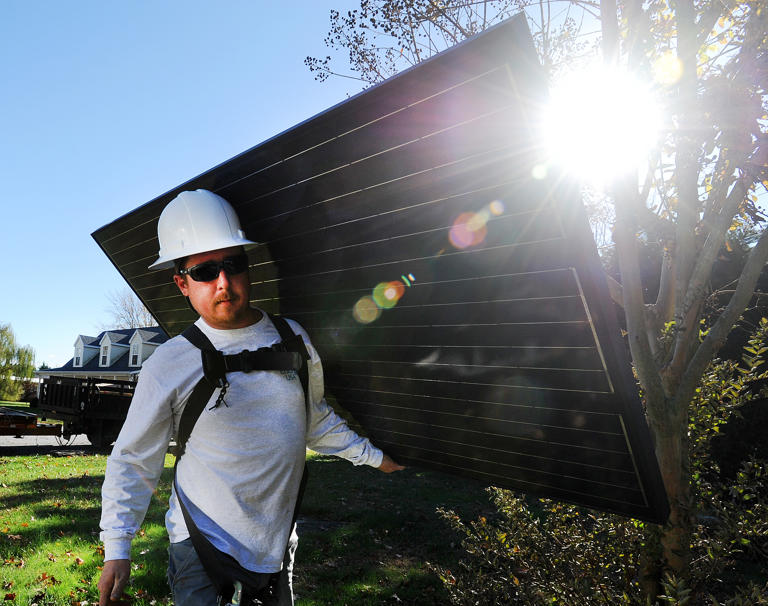 Back in 2014, Sean Morris of Clean Energy USA carries a solar panel to be installed at a home.