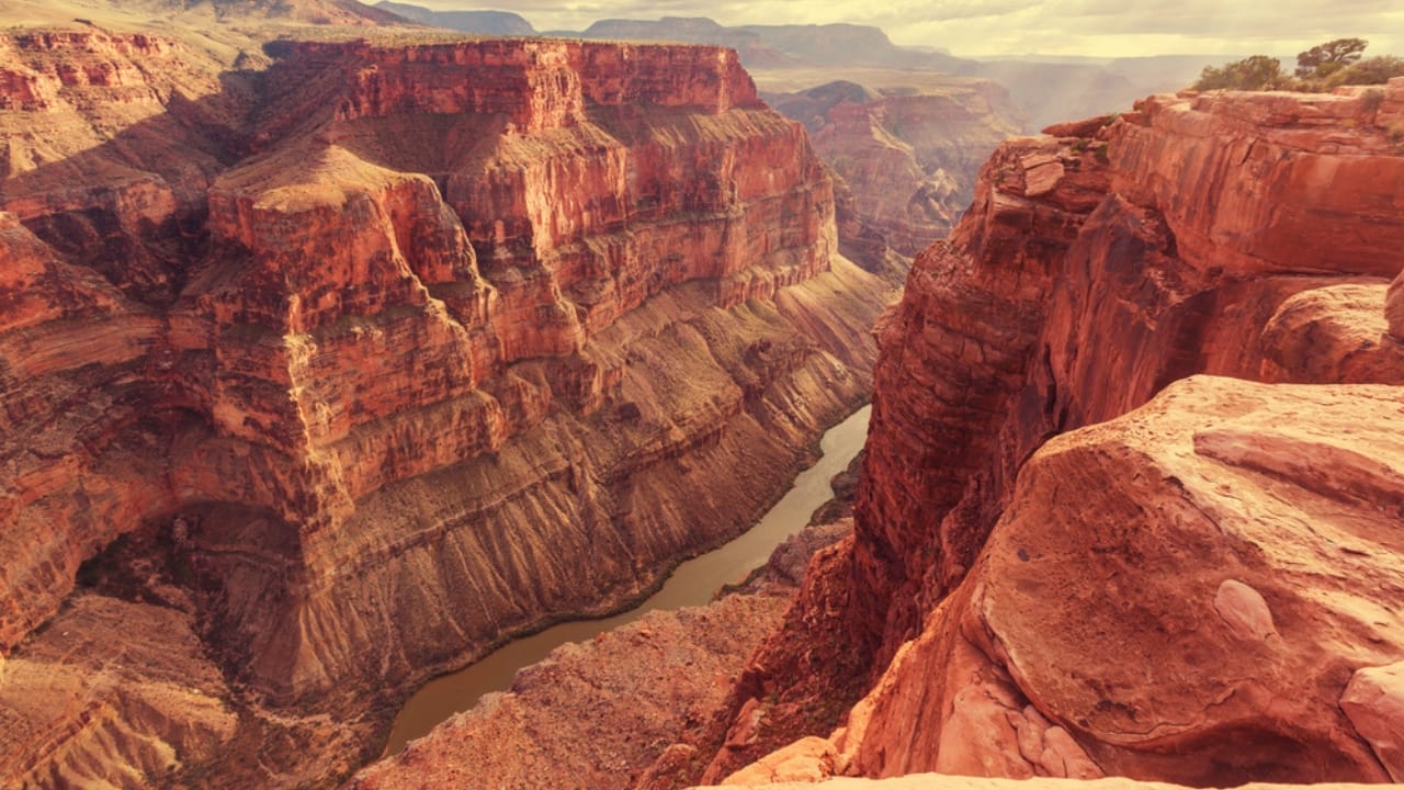 <p>The Grand Canyon is undeniably one of the most iconic and spectacular canyons in the world. Stretching over 277 miles in length and reaching depths of over a mile (6,000 feet), it offers an overwhelming panorama of layered red rock that documents millions of years of geological history. </p> <p>The Colorado River, which snakes through the canyon, has shaped this monumental landscape over an estimated five to six million years.</p> <p>Visitors to the Grand Canyon can experience a range of activities, from breathtaking helicopter rides that offer a bird’s-eye view of the canyon’s vastness to challenging hikes leading to remote rims. The park’s Skywalk, a glass bridge suspended 4,000 feet above the canyon floor, provides a thrilling perspective of the immense depth.</p>