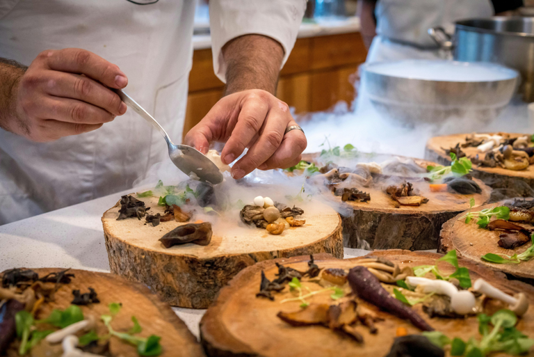 chef plating food on piece of wood