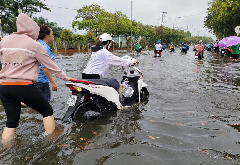 Xe công nhân bị chết máy do đường ngập sâu phải dắt bộ. Ảnh: Nam An