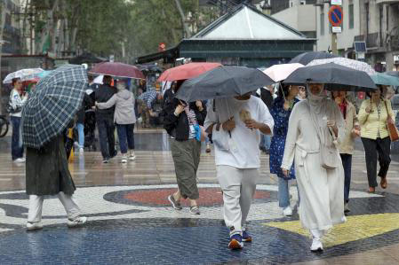 Varias personas se protegen de la lluvia mientras caminan por las Ramblas de Barcelona Toni Albir / EFE