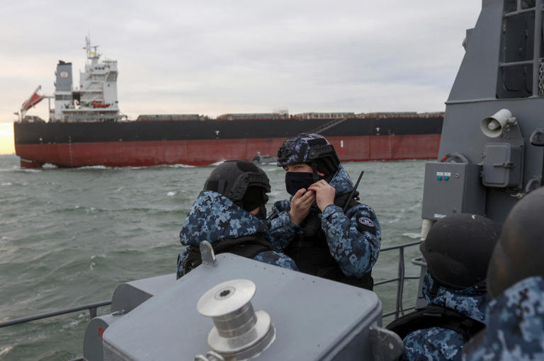 A servicemen of the Maritime Guard of the State Border Service of Ukraine adjusts his helmet during the inspection of a cargo ship for prohibited items and substances before entering a port in the northwestern part of the Black Sea, on 18 December 2023. Kyiv said a third of Russia's warships in the Black Sea have been sunk or disabled since the war began.
