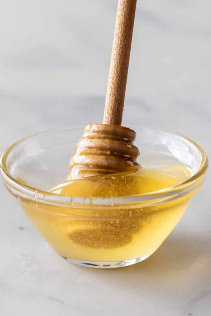 raw honey in clear bowl on white background - honey never expires
