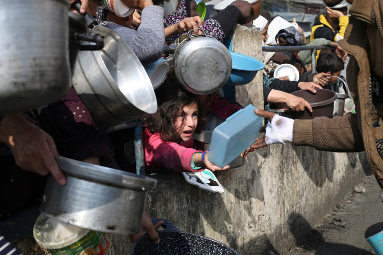 Palestinians line up for free food during the ongoing Israeli air and ground offensive on the Gaza Strip in Rafah (AP)