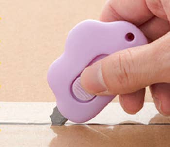 Model using a purple cloud shaped knife to open a package