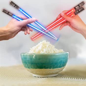Two sets of glowing lightsaber chopsticks in blue and red