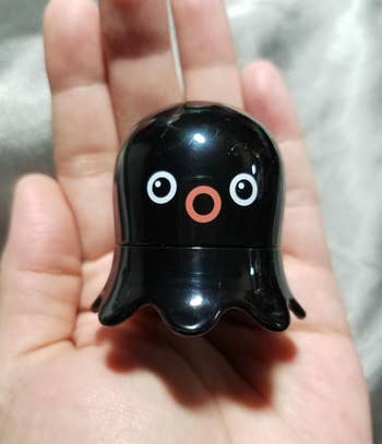 A black small octopus shaped remover in a reviewer's hand
