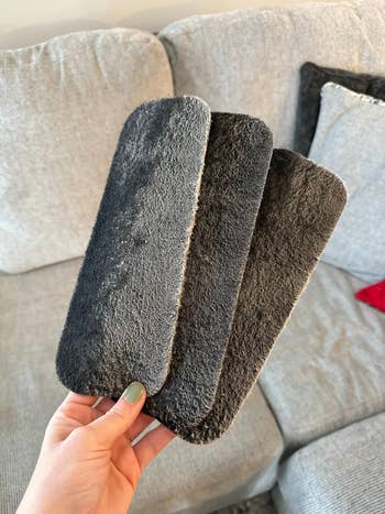 reviewer holding three used carbon filters covered in dust