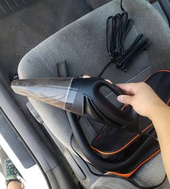 Small handheld black vacuum in a reviewer's hand