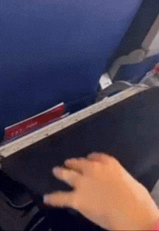 Model sliding black cover over a tray, which hangs with pockets the model puts a snack, laptop, and other devices into