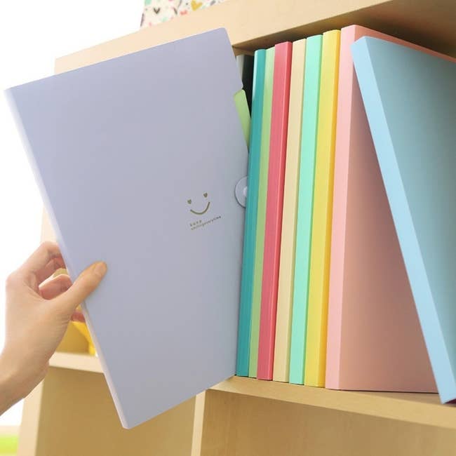 purple accordion folder with smiley face being pulled from bookshelf