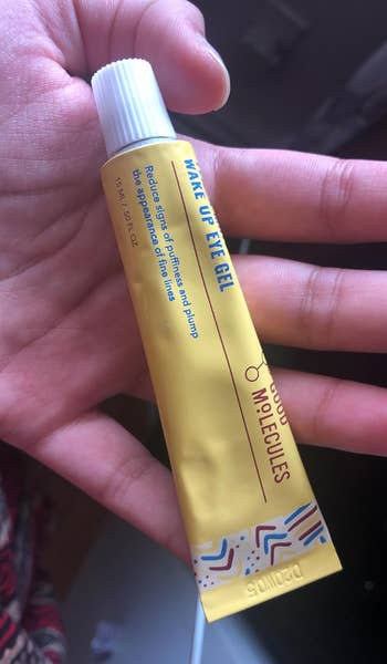 Hand holding a tube of eye cream