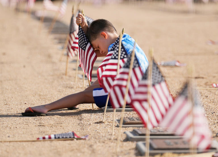 May 30, 2022; Phoenix, AZ, US; Andrew Vaught, 6, replaces a flag on a grave marker during a Memorial Day ceremony at the National Memorial Cemetery of Arizona. This was the first public Memorial Day ceremony since 2019.