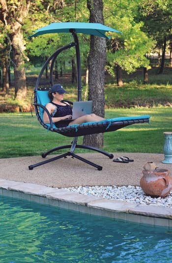 a reviewer sitting in a blue swing using a laptop
