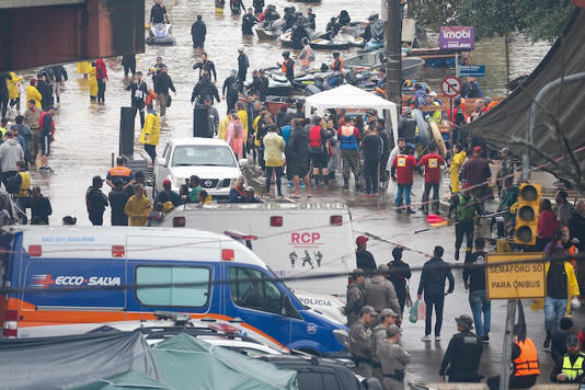 Voluntários tentam resgatar pessoas no bairro São João, em Porto Alegre; barcos e jetskis particulares circulam pelo bairro Foto: Wilton Junior/Estadão