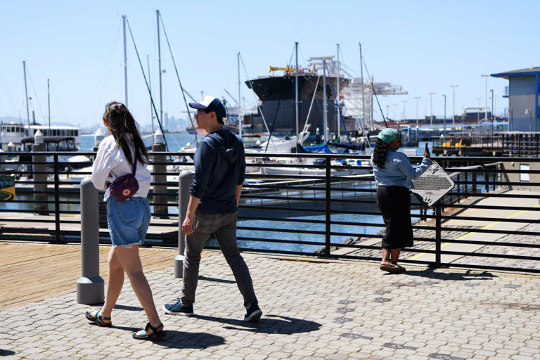 Visitors walk along the waterfront at Jack London Square in Oakland, Calif., on Monday, April 29, 2024. In the background the Howard Terminal can be seen in the distance. Now that the Oakland A’s stadium development is unlikely to happen the future is unsure for local businesses in the Oakland waterfront area.