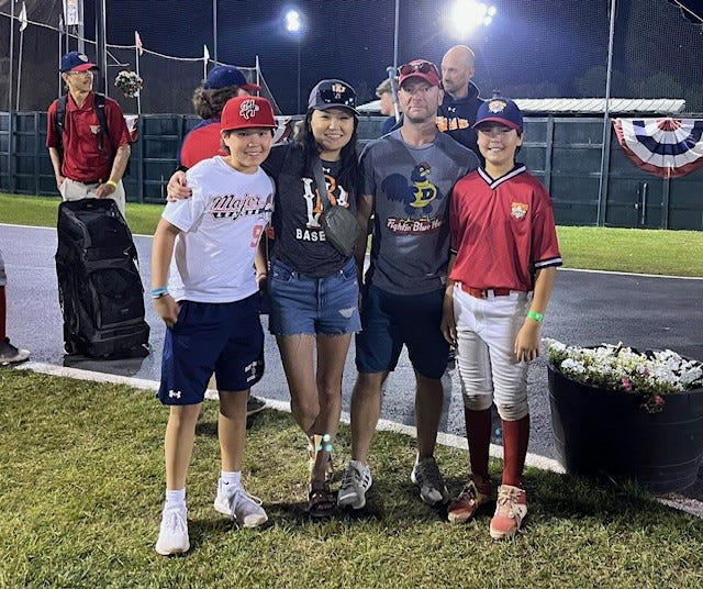 Dana Yoo (center left) poses, left to right, with her son Caius, husband Chris, and son Marcus at a tournament in Cooperstown, New York, during the summer of 2022.