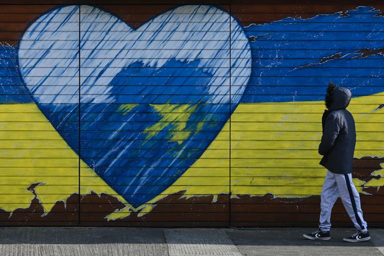 A young boy walks past a mural related to the war in Ukraine
