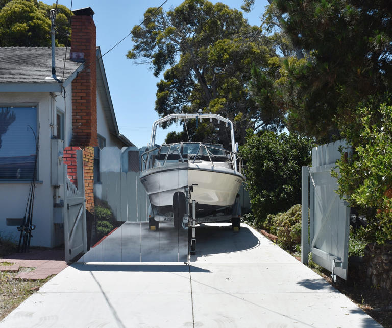 The opposite half of Etienne Constable's boat is visible from behind a hyper-realistic mural, painted by next-door neighbor Hanif Panni. The two men decided to make the mural to comply with a city rule in a creative way.