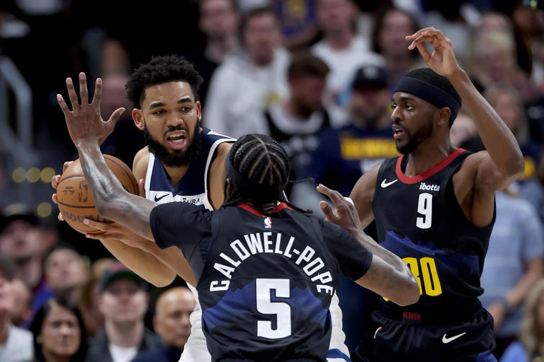 The Minnesota Timberwolves' Karl-Anthony Towns, top left, comes under pressure during the first quarter against the Denver Nuggets' Justin Holiday and Kentavious Caldwell-Pope in Game 5 of the Western Conference second-round playoff series at Ball Arena on Tuesday, May 14, 2024, in Denver.