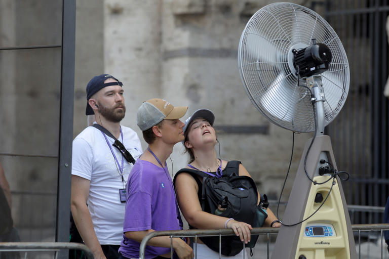 Tourists cool off in front of a fan in Rome, Italy on July 18, 2023. Temperatures in the area at the time surpassed 104 degrees Fahrenheit.