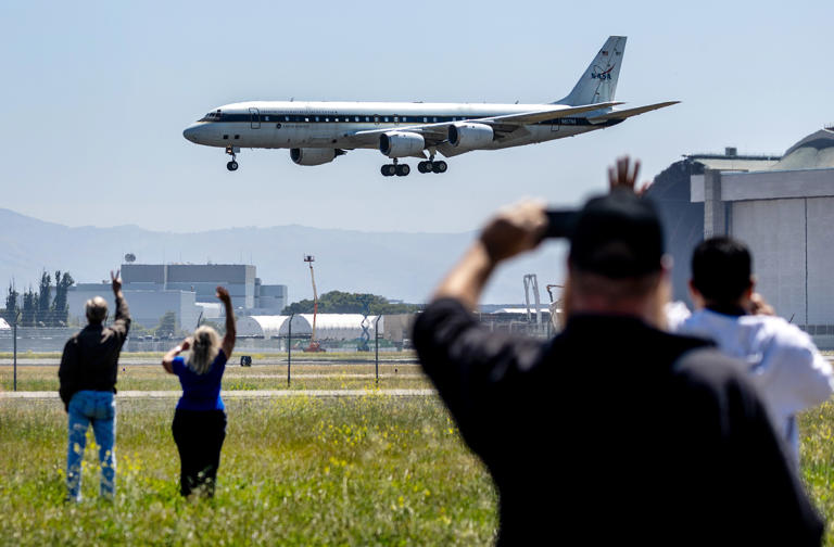 Ames Research Center’s Chris Scofield and Mike Gaunce wave goodbye to NASA’s venerable DC-8 Flying Laboratory as it makes a final flyby at Moffett Field, Wednesday, May 15, 2024, in Mountain View, Calif.