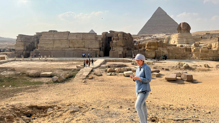 Professor Enam Ghoneim onderzoekt de topografie bij de oude riviertak, met op de achtergrond de piramide van Cheops en de sfinx in Gizeh.