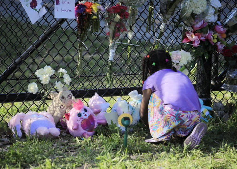 A girl lays down flowers at a makeshift memorial at Sugar Mill Elementary in Port Orange where a fourth-grade girl was hit by an SUV and later died on Friday, May 24, 2024.