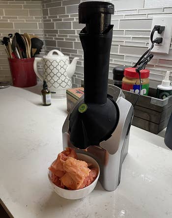The black device on a table with sorbet in a bowl under it