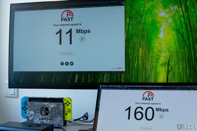 Two computers running a speed test on fast.com. One of the computers, the Geekom A8, only reaches speeds of 11Mbps, while the other is at 160Mbps.