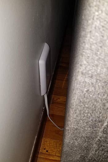 a reviewer photo of the slim outlet cover with a piece of furniture up against the wall