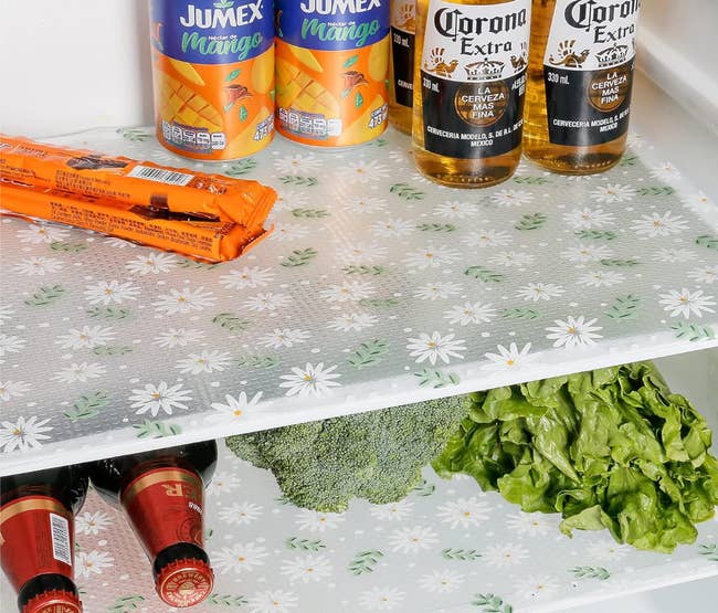 Fridge shelves lined with a transparent liner with a white and green leaf and daisy print