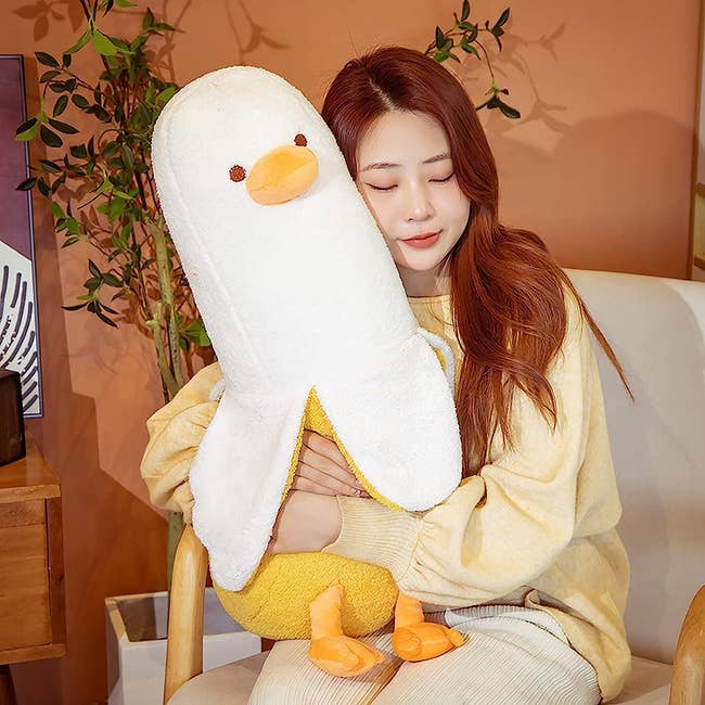 a model hugging a large banana duck plushie