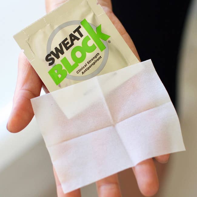 hand holding a package of Sweat Block wipes