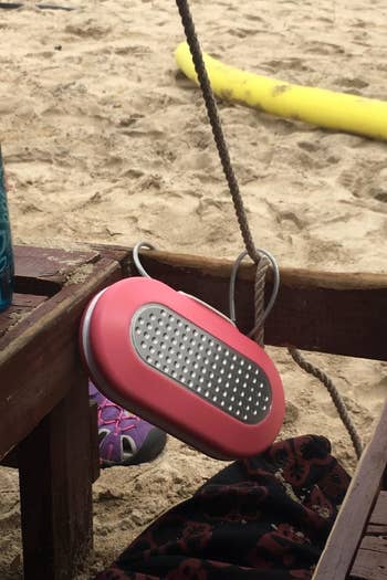 reviewer's pink personal safe that's attached to a beach chair at the beach
