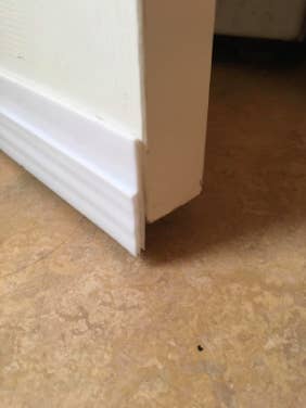 reviewer's close up of white door draft stopper on the bottom of the door