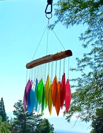 Multicolored wind chimes hanging outdoors with a scenic backdrop