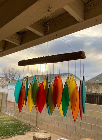 Colorful leaf-shaped wind chime hanging outdoors with sunset in the background