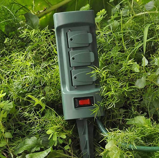 the power stake in a bush outside with the covers over each outlet